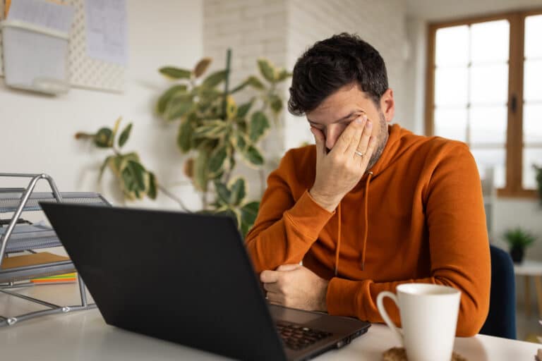 Man tired sitting in front of laptop struggling with porn addiction